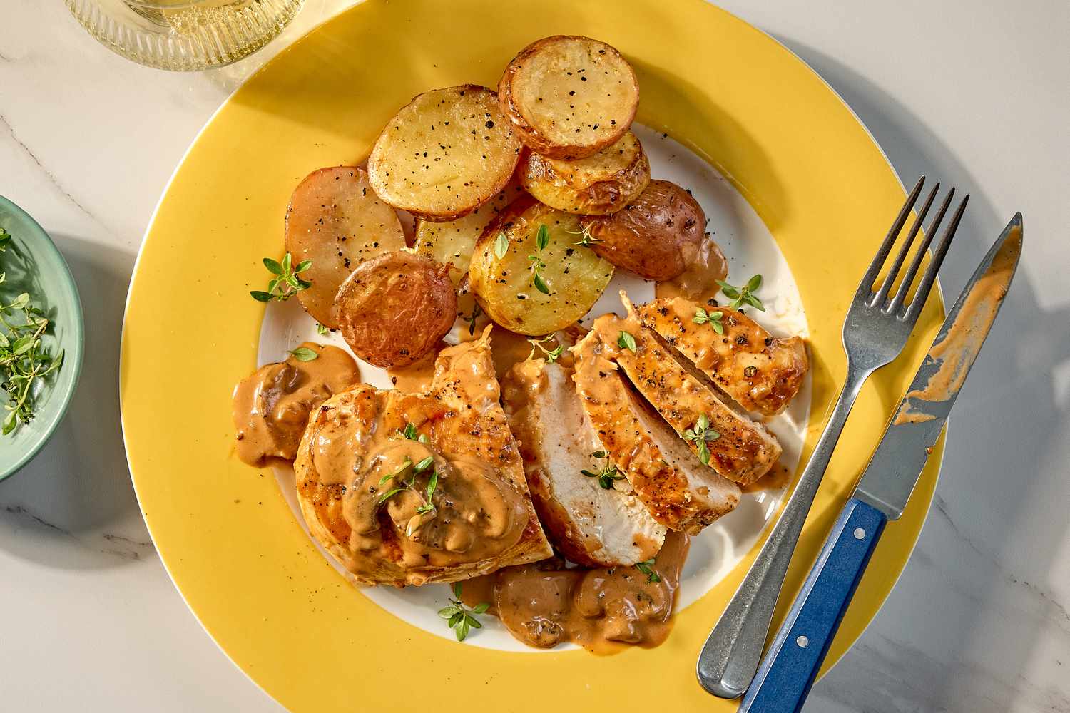 Plated chicken Diane served with roasted potatoes and garnished with herbs