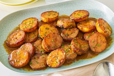 Baked sliced miso melting potatoes in a light blue serving plate, dressed in a miso sauce