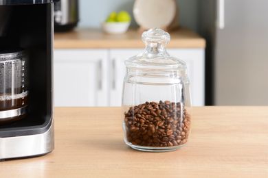 A glass jar with coffee beans on a wooden table