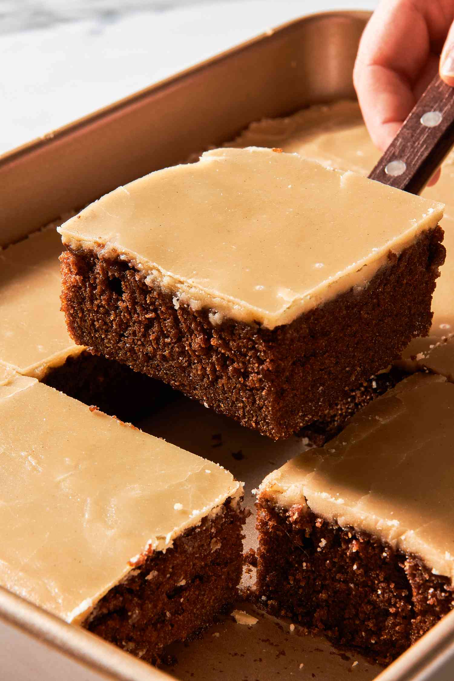 Dr. Pepper cake cut into squares with one square lifted using a spatula