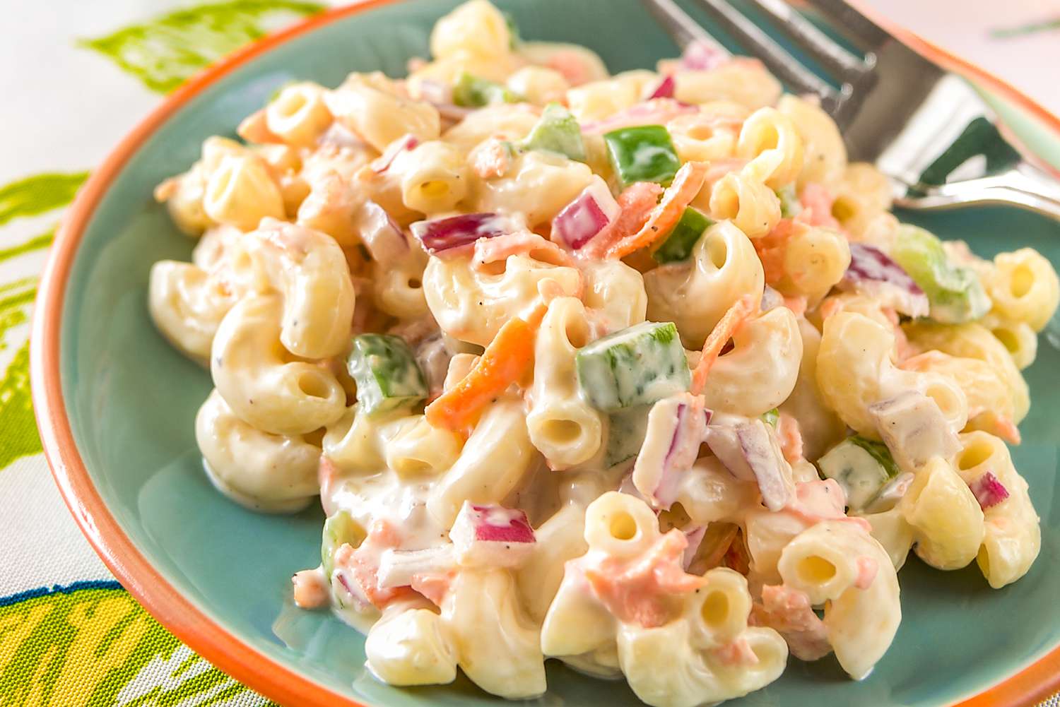 Plate of creamy macaroni salad on a table with a fork