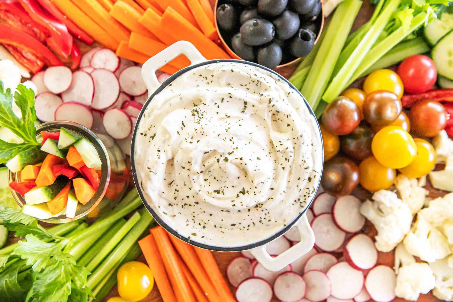 A crudités spread with a dip bowl of ranch dip in the middle