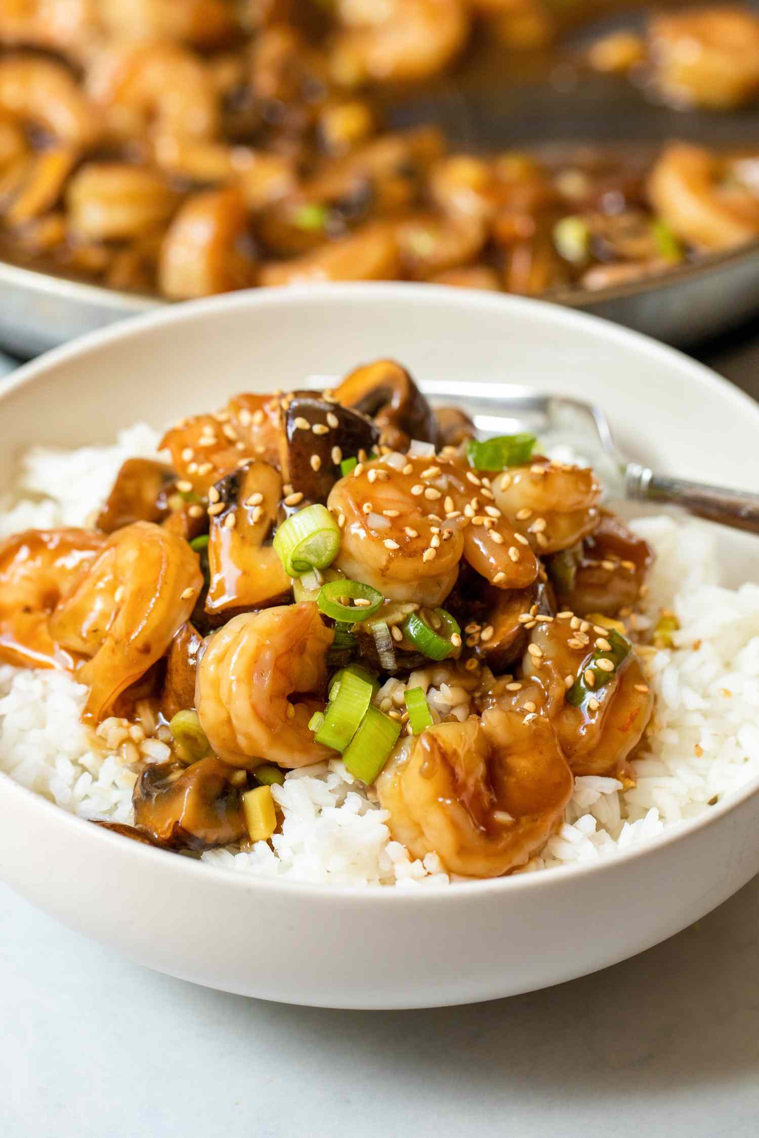 Shrimp and Mushroom Stir Fry Served over Rice and in the Background, a Skillet with More Stir Fry