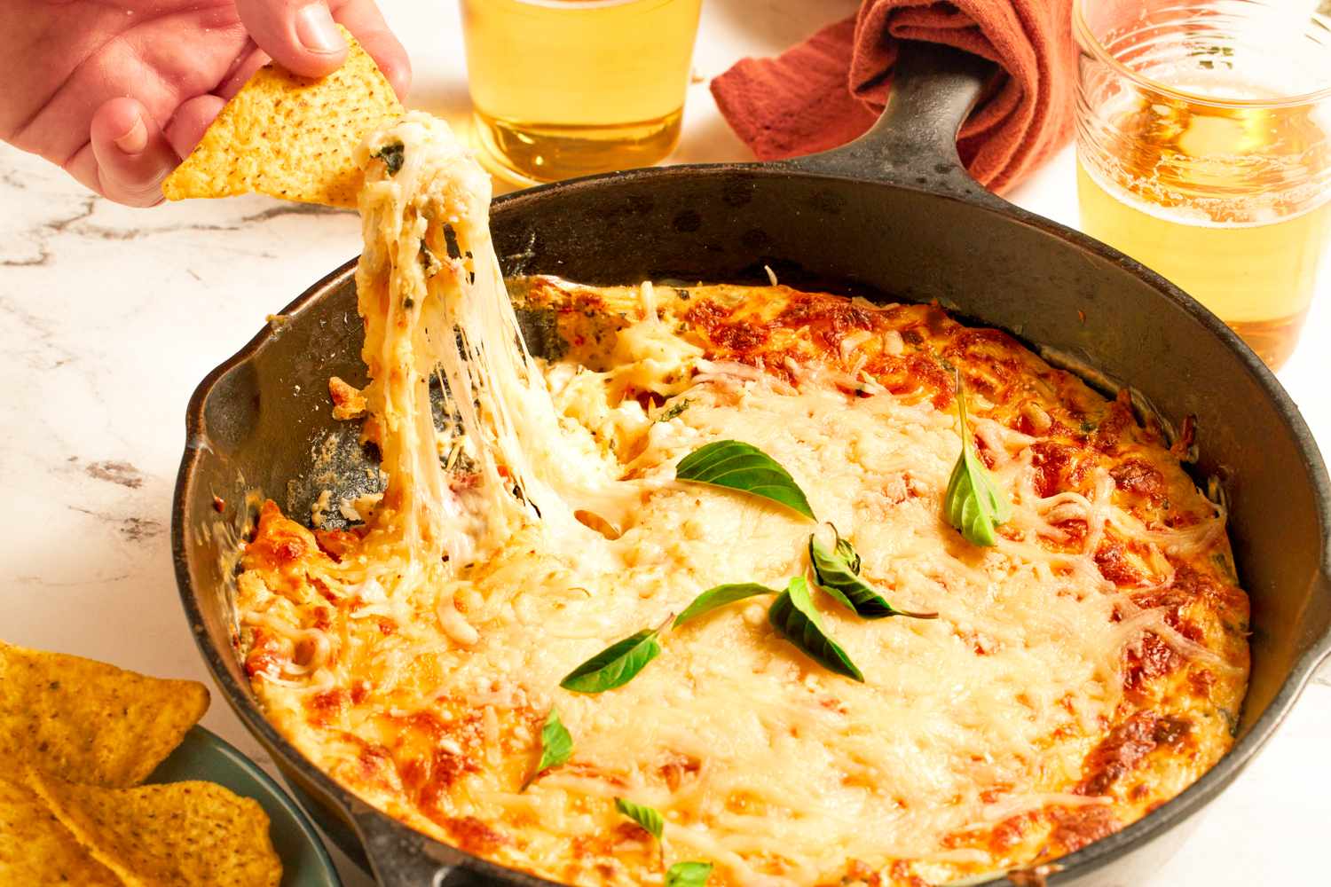 Cheesy dip in a skillet with chips being dipped in