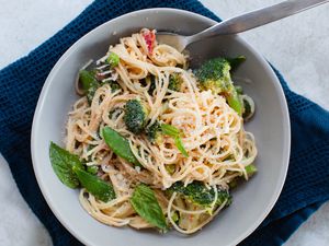 Overhead view of primavera pasta in a bowl with a navy linen underneath.