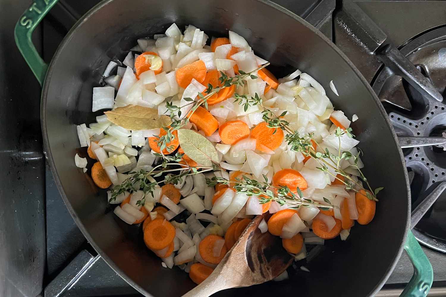 Onions, Carrots, Bay Leaves, and Thyme Sprigs in a Dutch Oven to Make Soup Base for Vegan Butternut Squash Soup Recipe 