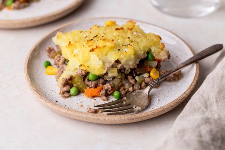 A piece of shepherds pie on a plate with a fork.