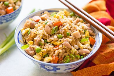 Bowl of fried rice at a table setting with utensils, table napkins, and more bowls of rice
