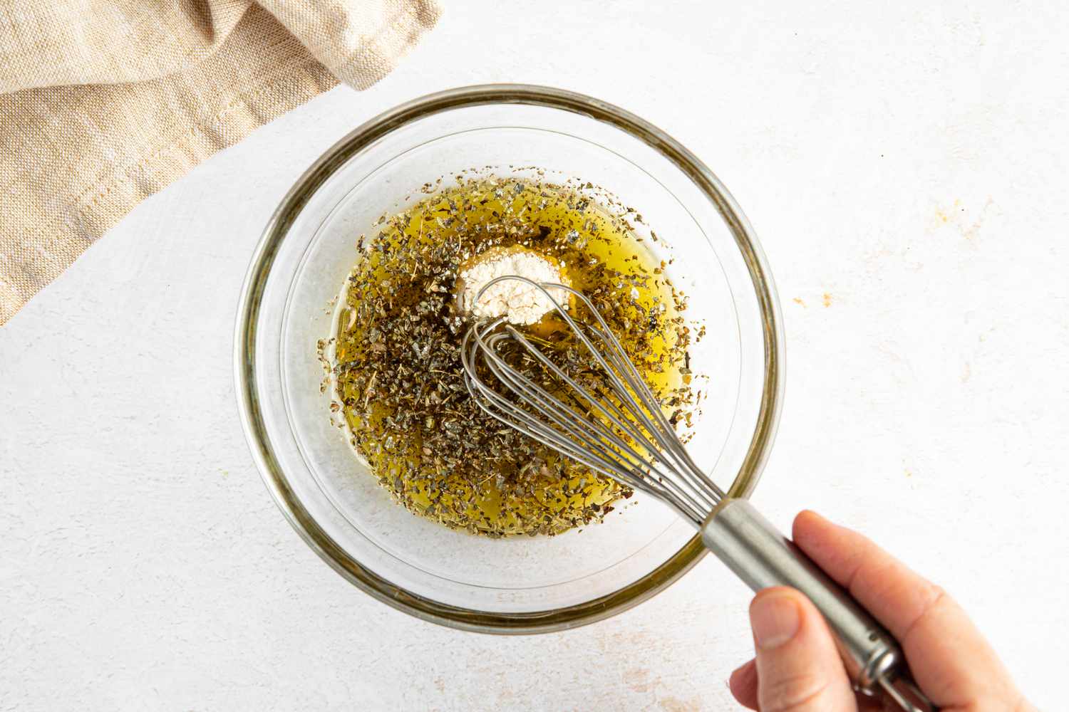 Seasoning and oil whisked together in a bowl for croutons from sheet pan caesar salad recipe
