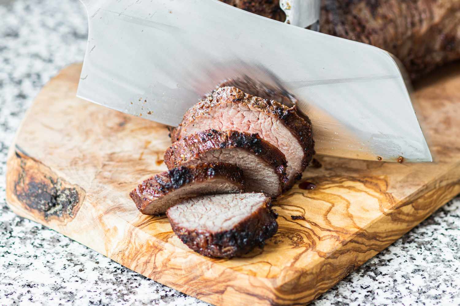 Slicing a tri tip steak on a cutting board.