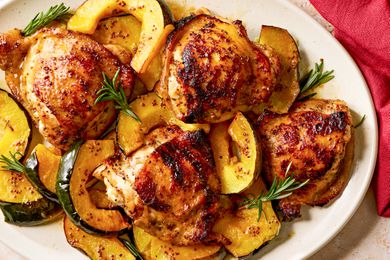 Overhead view of a white platter of maple glazed chicken and squash next to a red cloth napkin