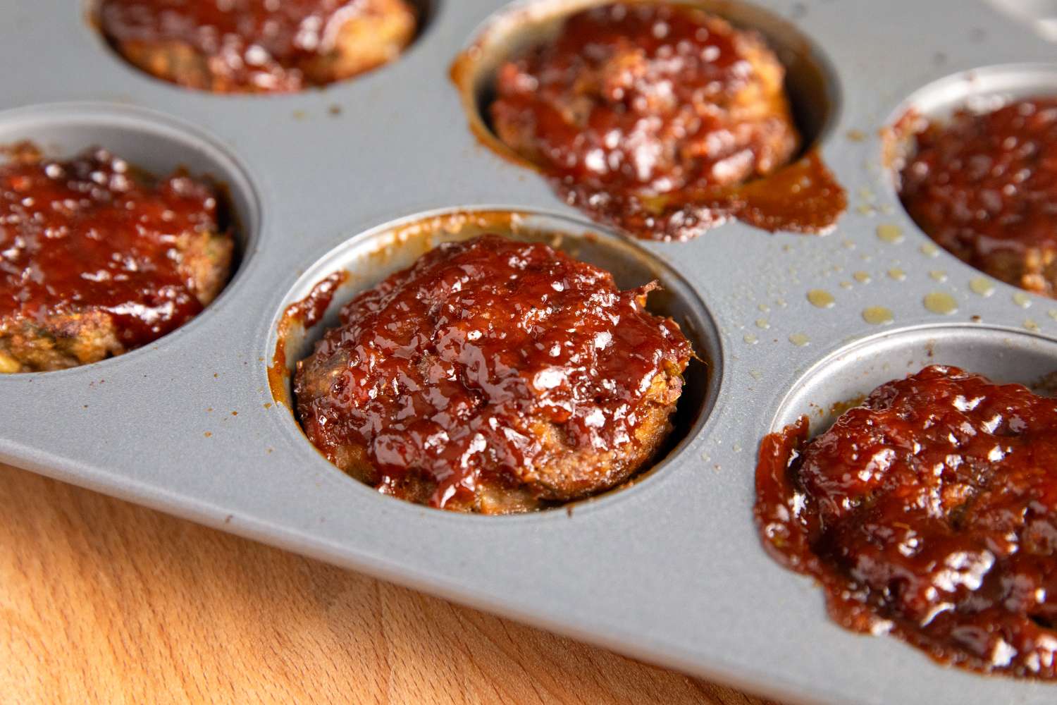 Meatloaf muffins in a baking tray with a glazed topping