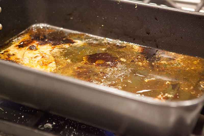 A baking dish with excess bird drippings and fat