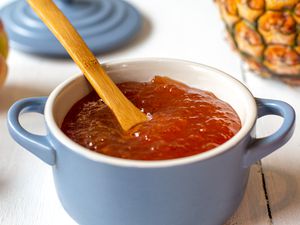 Peach and Pineapple Jam in a Small Dutch Oven Surrounded by Peaches and a Pineapple 