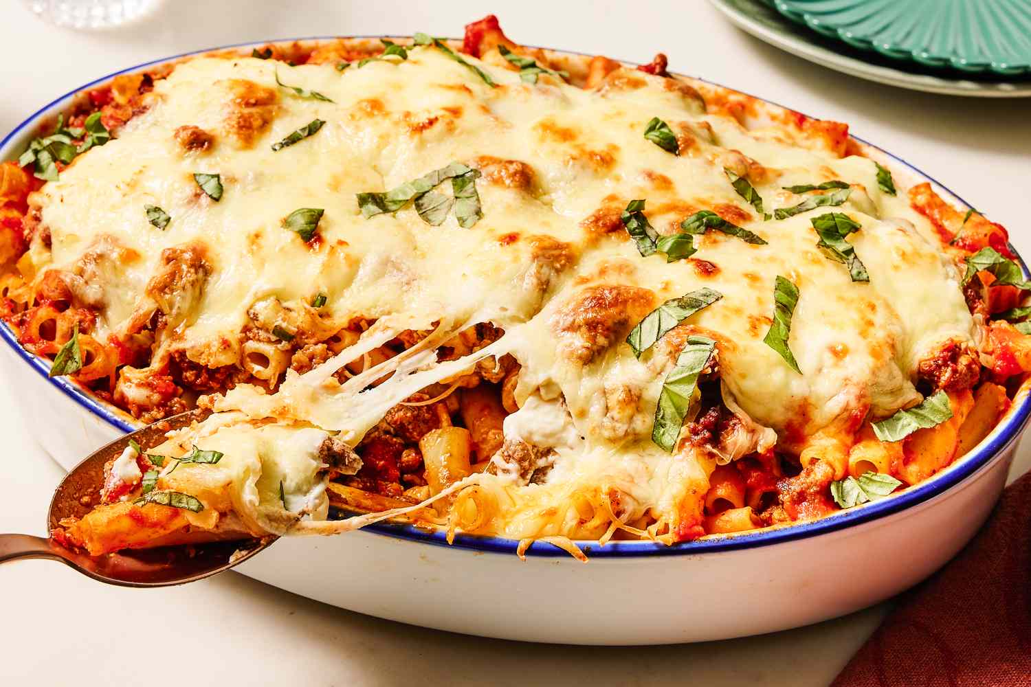A baked ziti dish with melted cheese and garnished with herbs served in a casserole dish