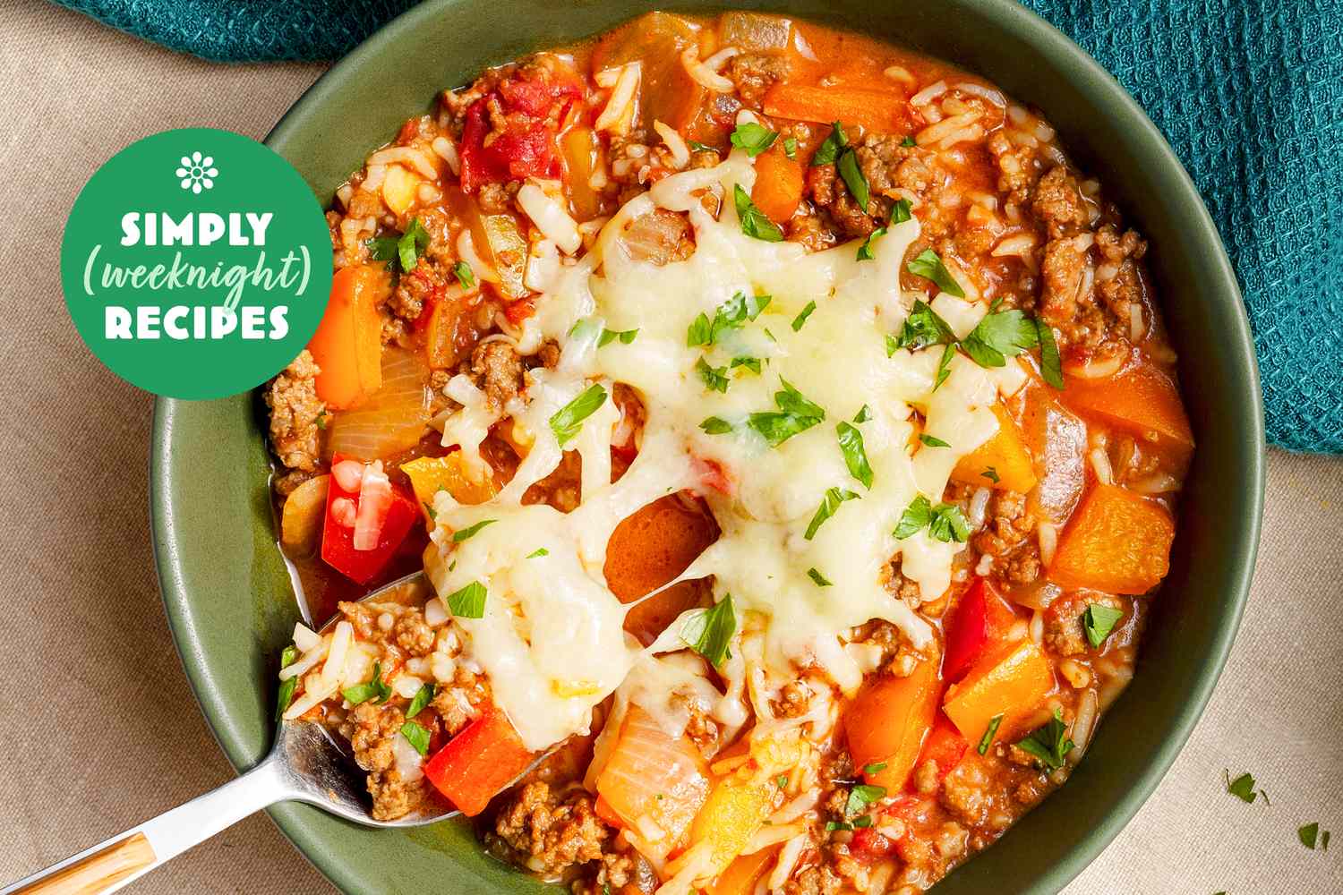 A bowl of hearty soup topped with melted cheese and parsley featuring meat vegetables and rice