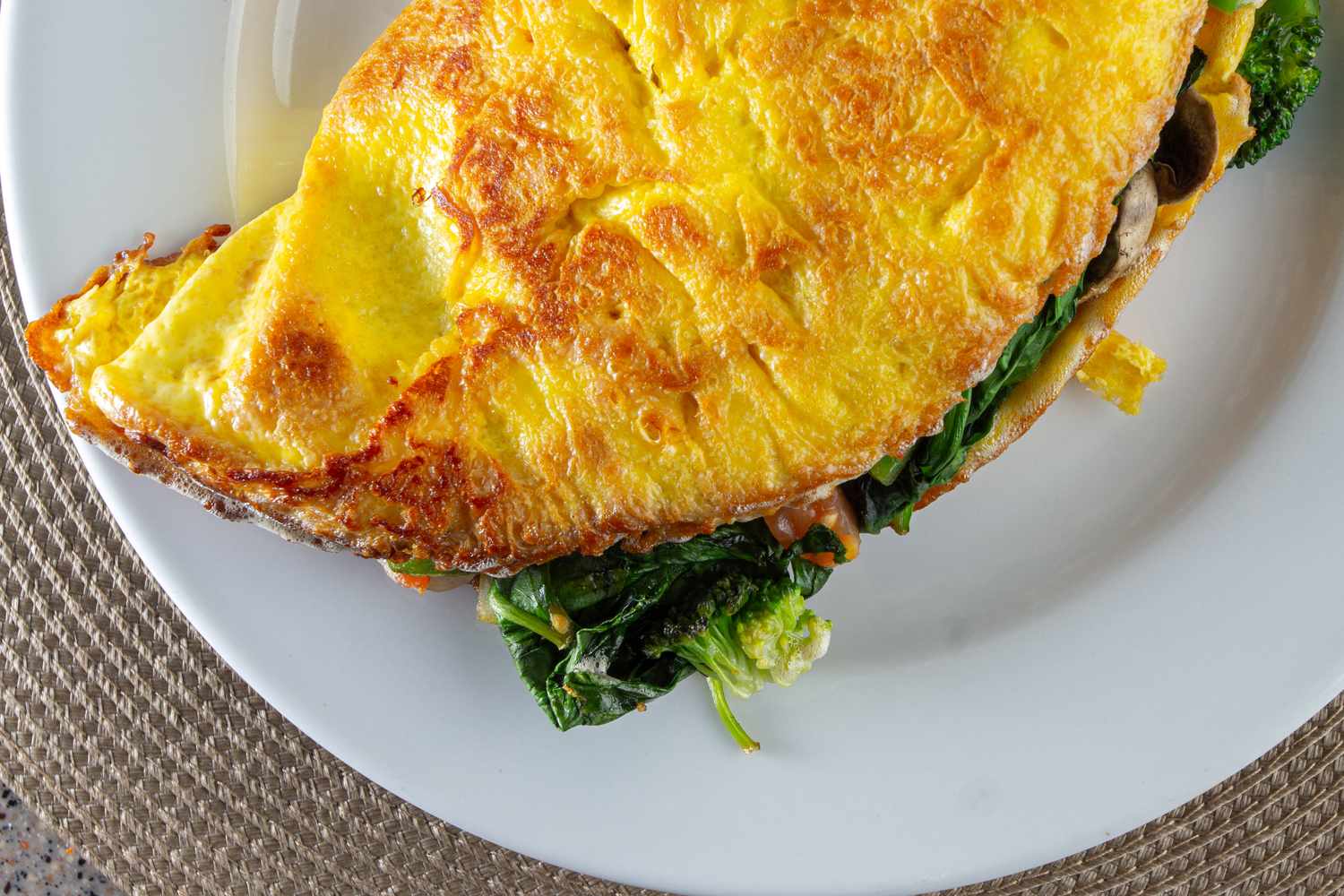 A closeup of an omelet with greens on a white plate