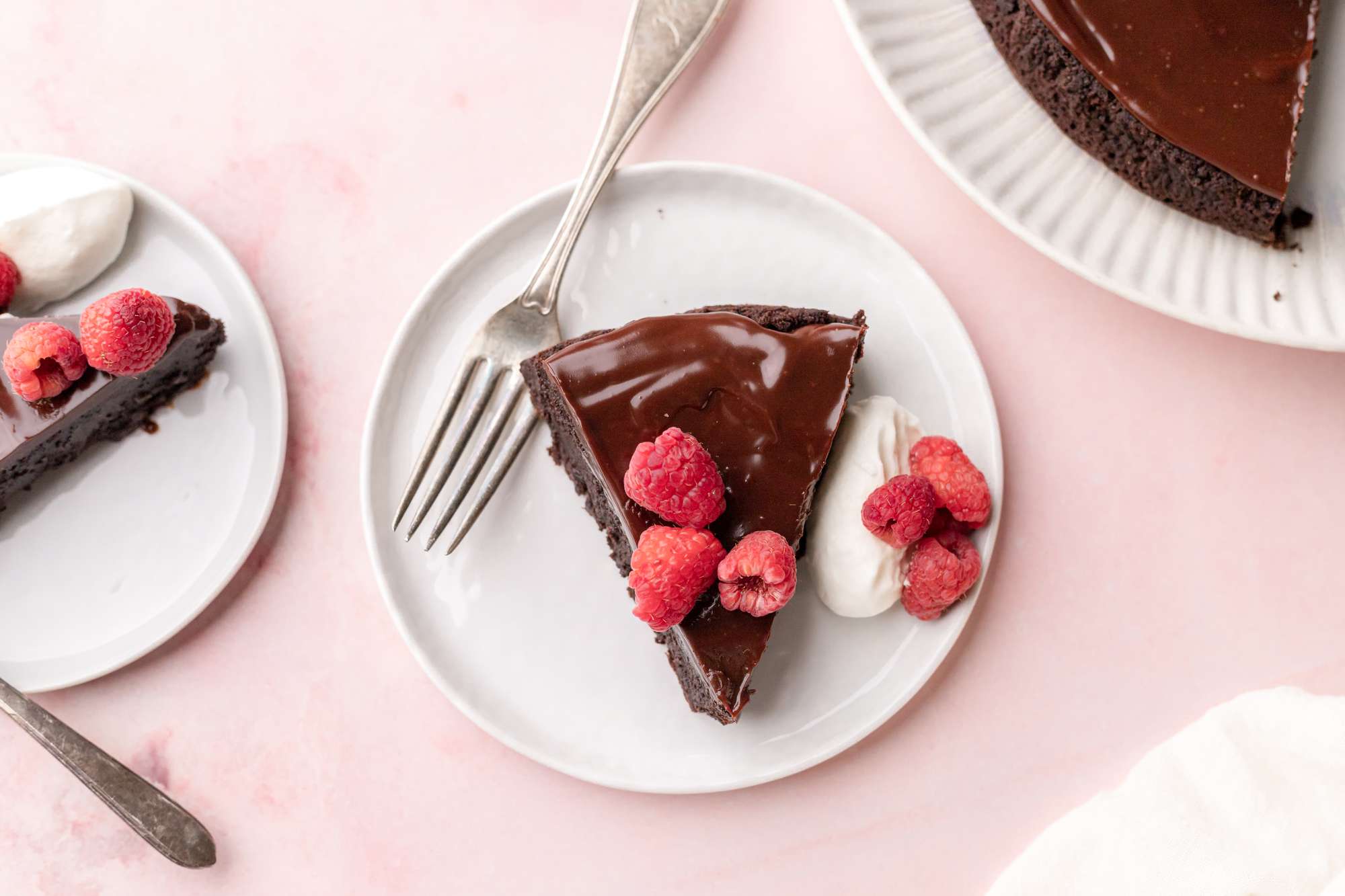 Slices of Flourless Chocolate Cake Served on a Small Plate with Fresh Raspberries and Whipped Cream