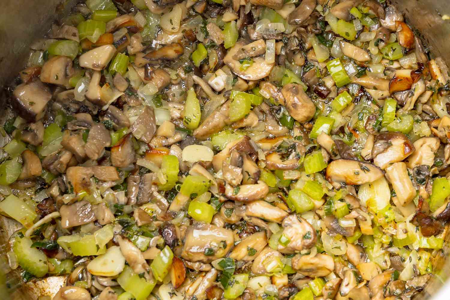 Celery, Onion, Scallions, Celery, Garlic, and Herbs Added to Pot of Mushrooms for Mushroom Stuffing Vegan Recipe