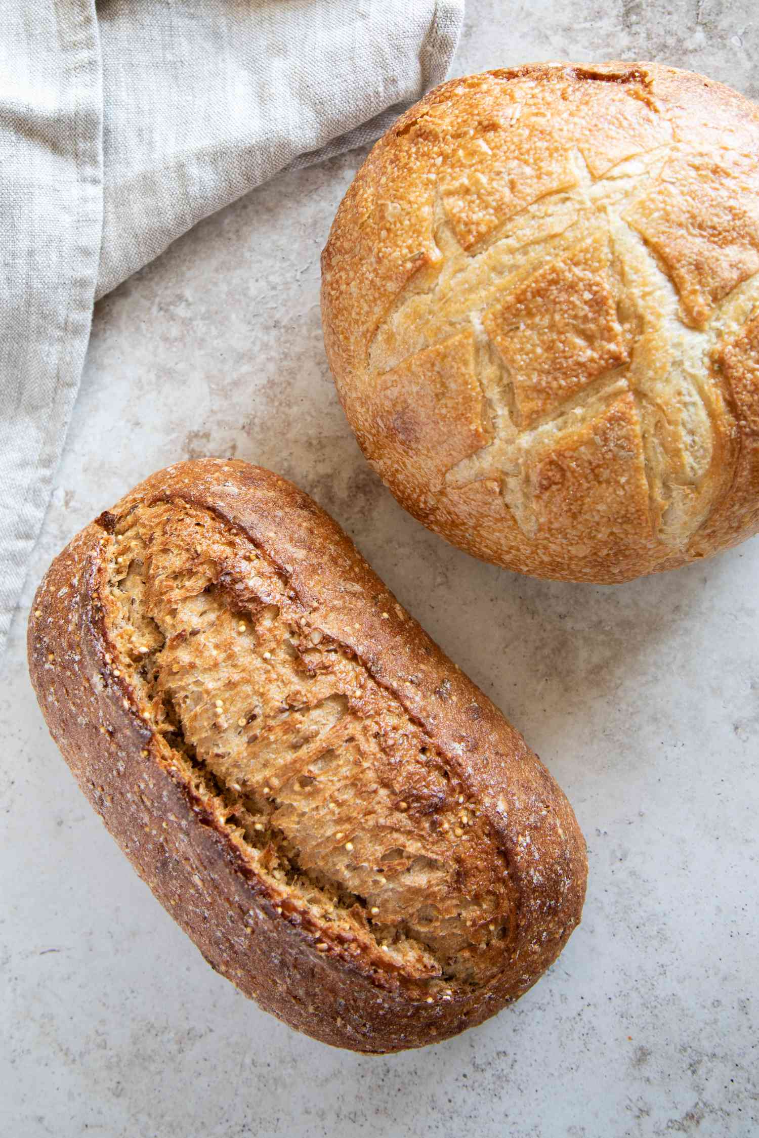 Two artisan loaves of bread on marbled surface