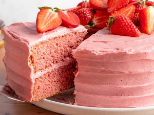 slice of strawberry cake lifted from the rest of the cake using a pie server