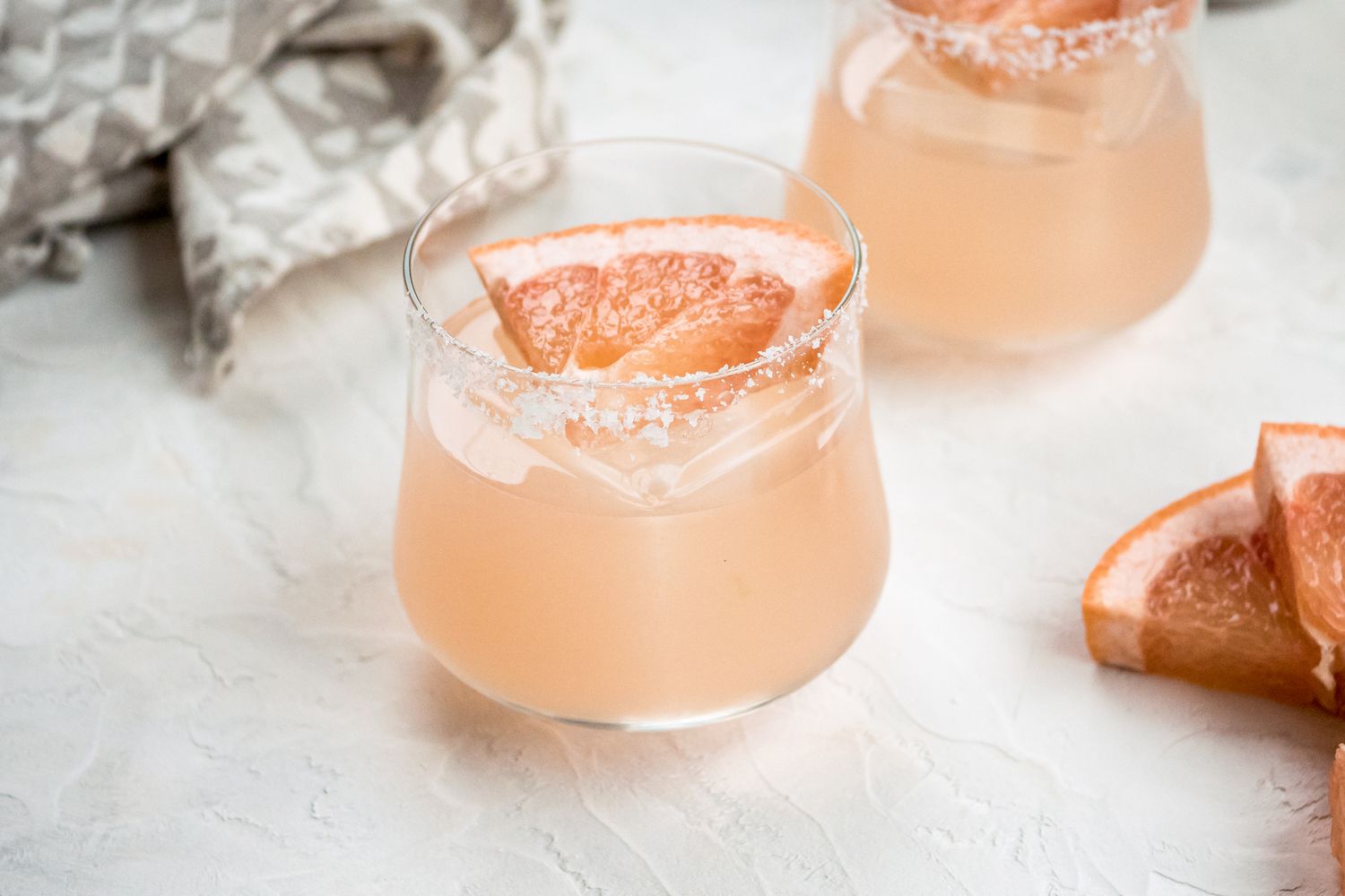 Two delicious grapefruit margaritas garnished with a grapefruit wedge.