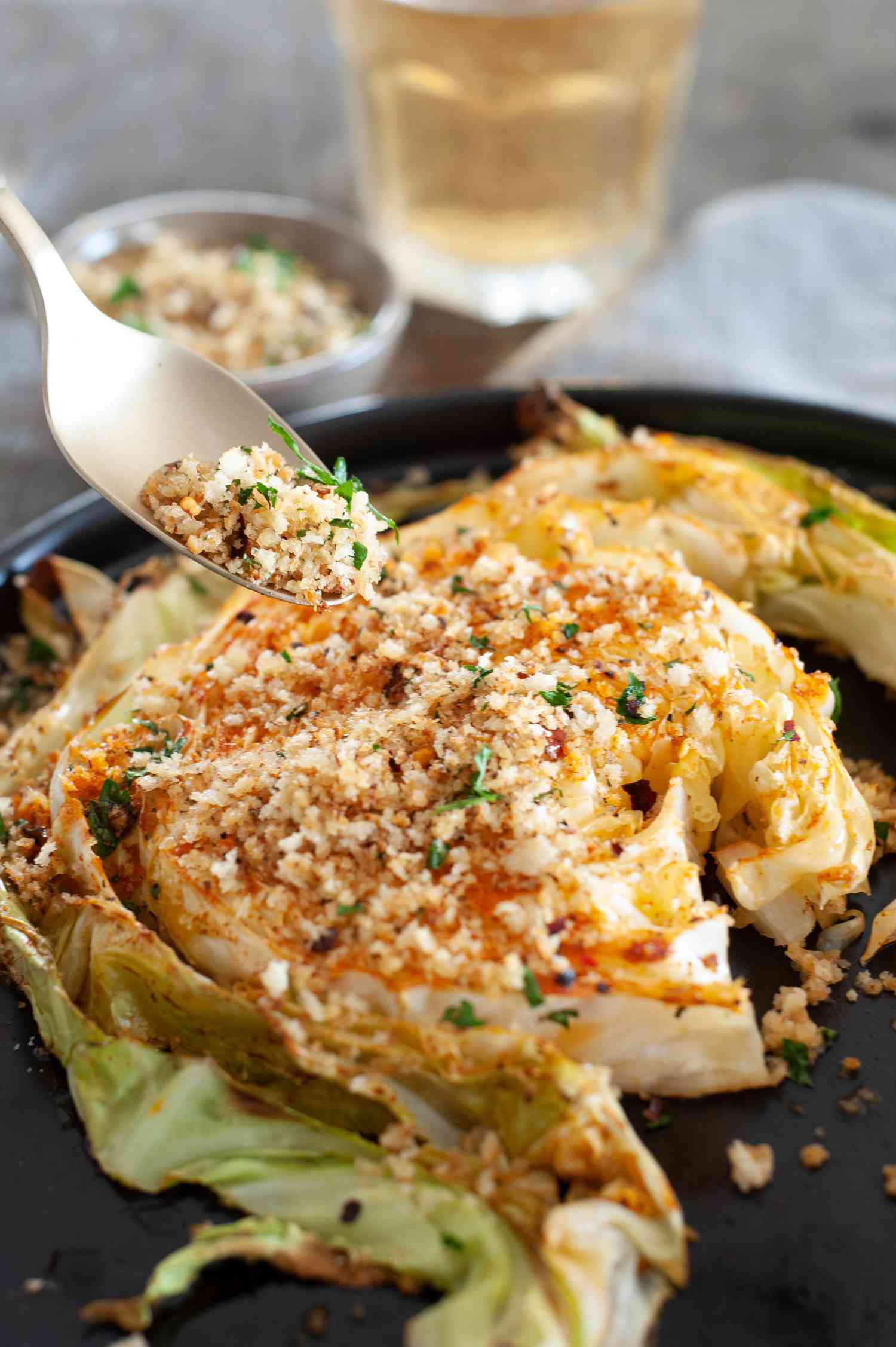 Spooning topping over roasted cabbage steaks.