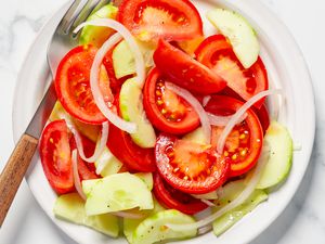 A plate of tomato, cucumber, and onion salad with a fork