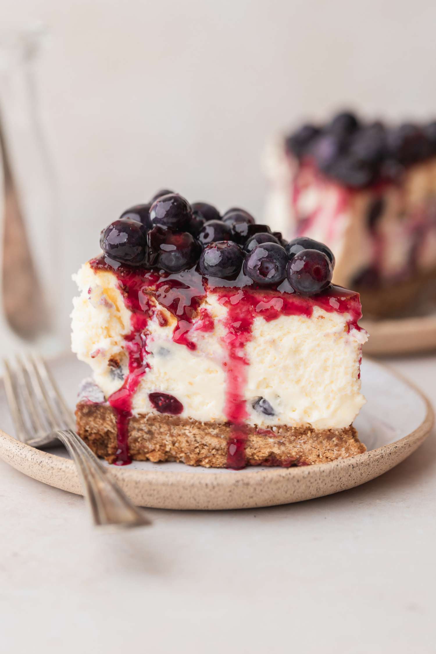 single slice of blueberry cheesecake on plate with a fork