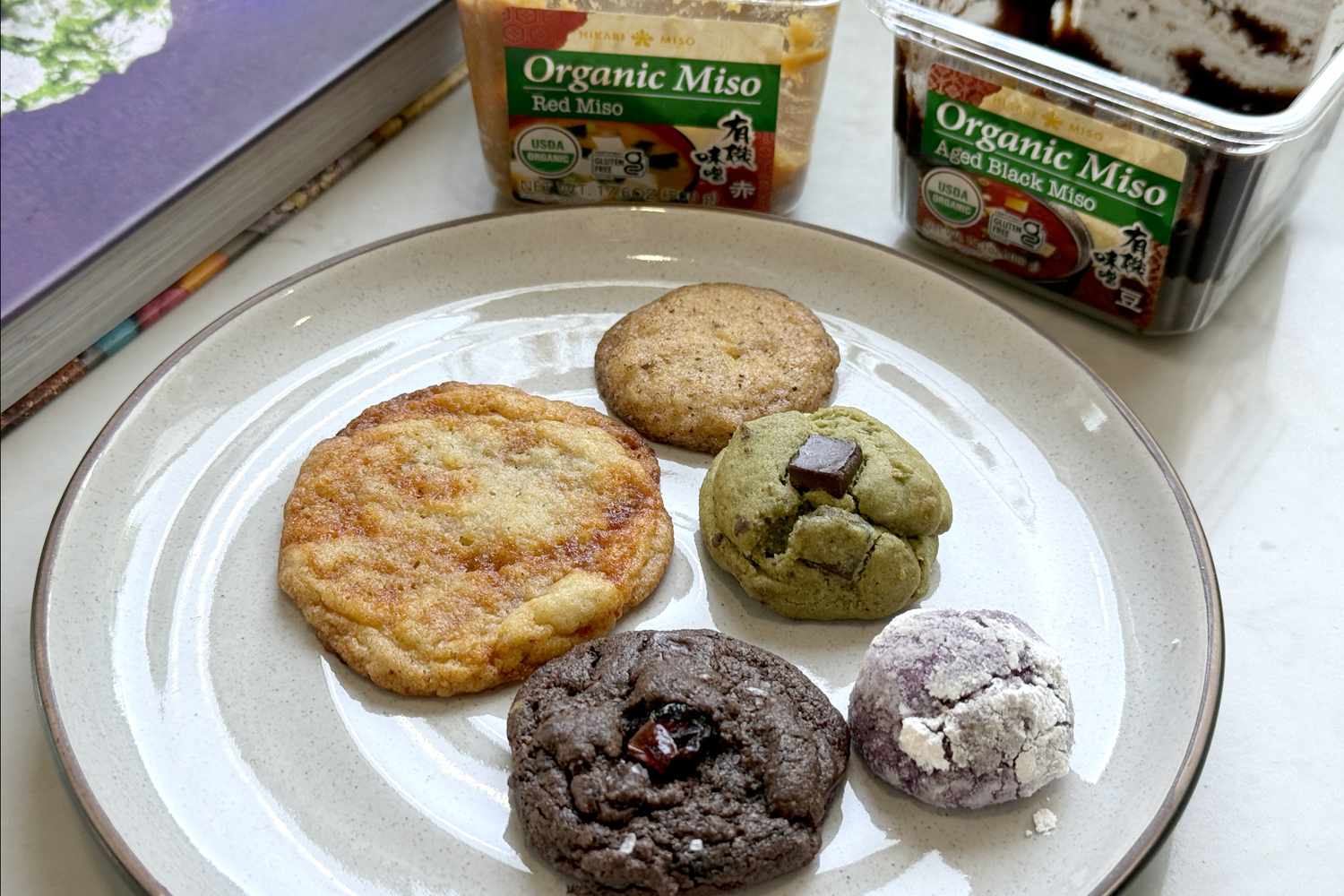 Assorted cookies on a plate with organic miso containers in the background