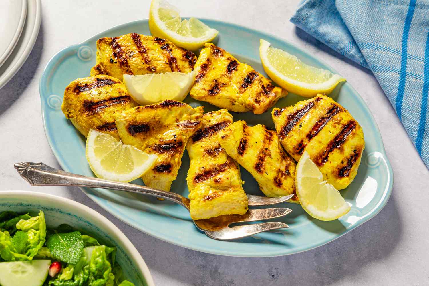 Grilled chicken pieces with lemon wedges on a plate
