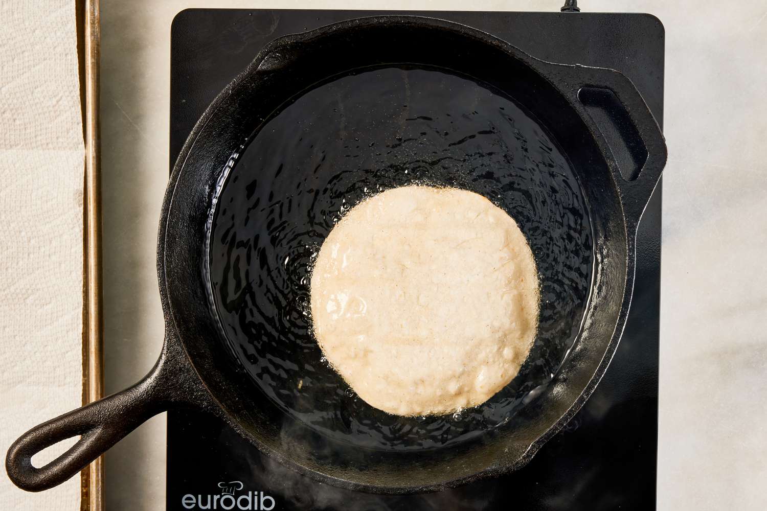 corn tortillas shallow frying in a cast iron skillet for crispy ground beef recipe 