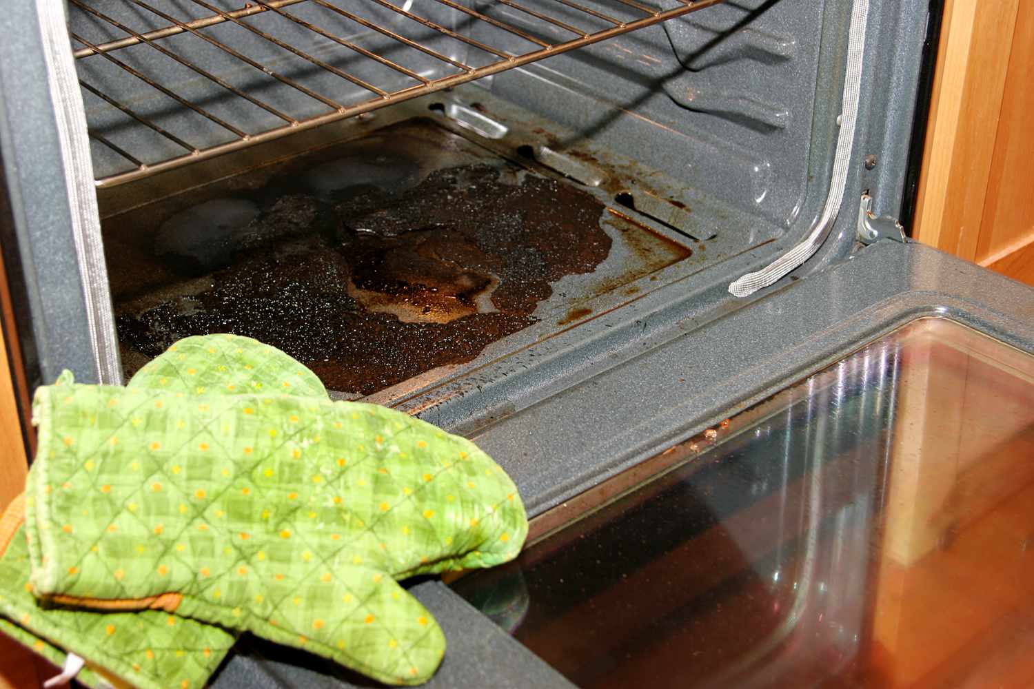 A dirty oven with oven mitts in the forefront