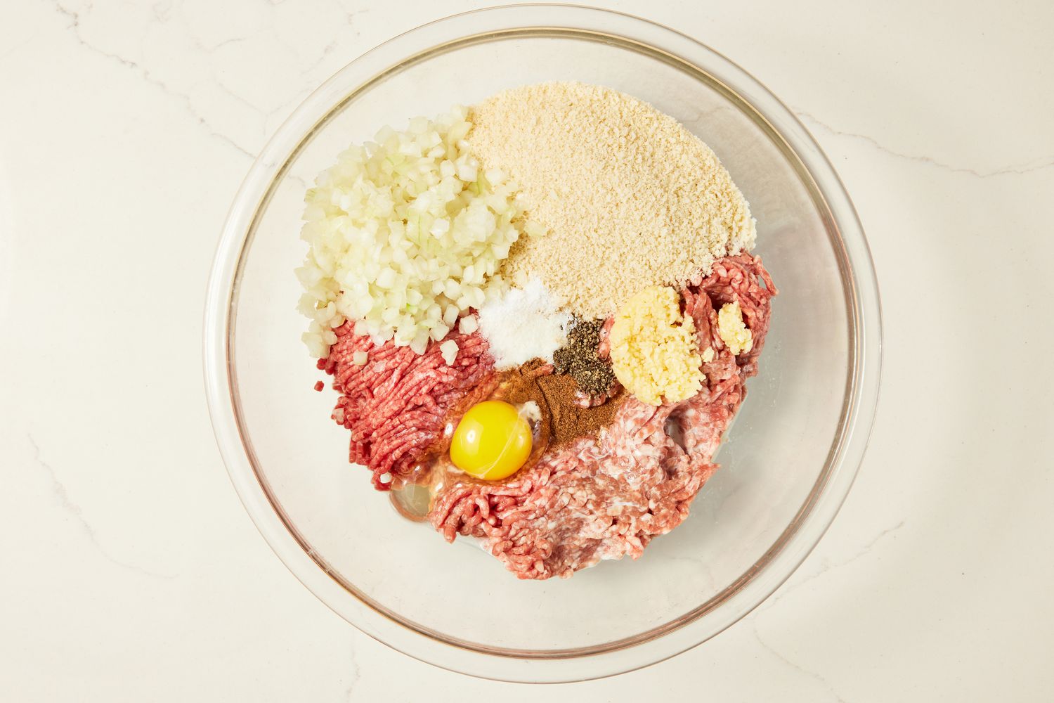 Ground beef, ground pork, onions, eggs, panko breadcrumbs, and seasoning in a bowl for copycat Ikea meatballs recipe