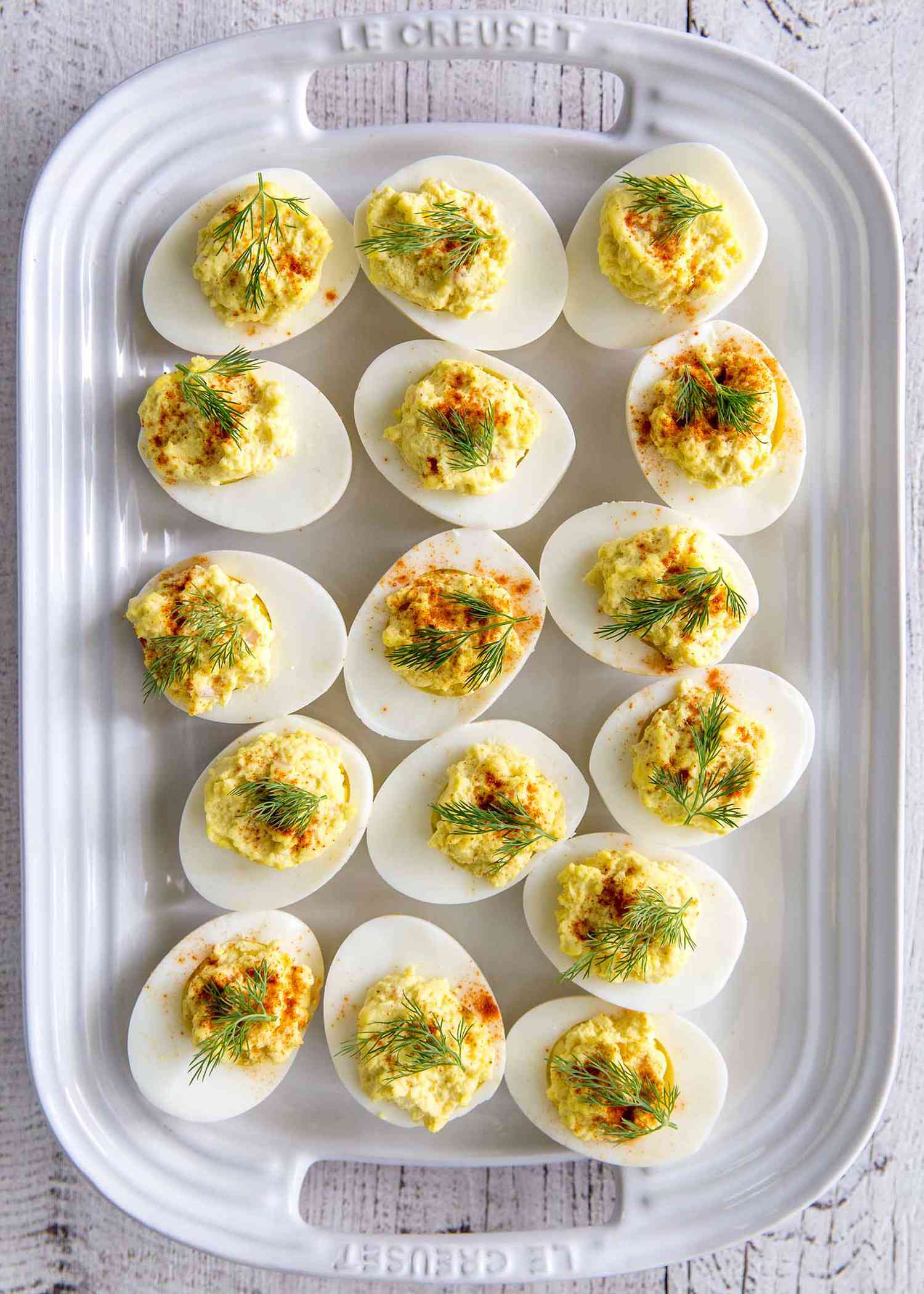 Simple Deviled Eggs with Horseradish - top down - Close up of deviled eggs with dill and paprika on a white platter