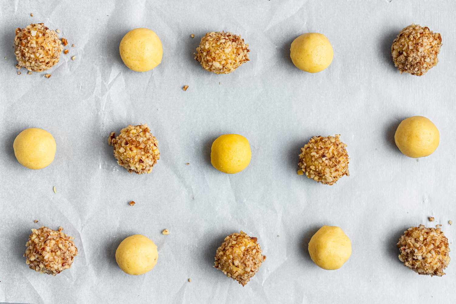 Thumbprint cookie dough rolled into balls and some of them rolled in nuts.