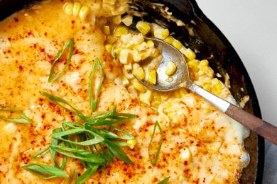 Close-up: Cast Iron Skillet With Korean Corn Cheese Topped With Sliced Green Onions and a Spoon (After Some of the Korean Cheese Corn Was Served)