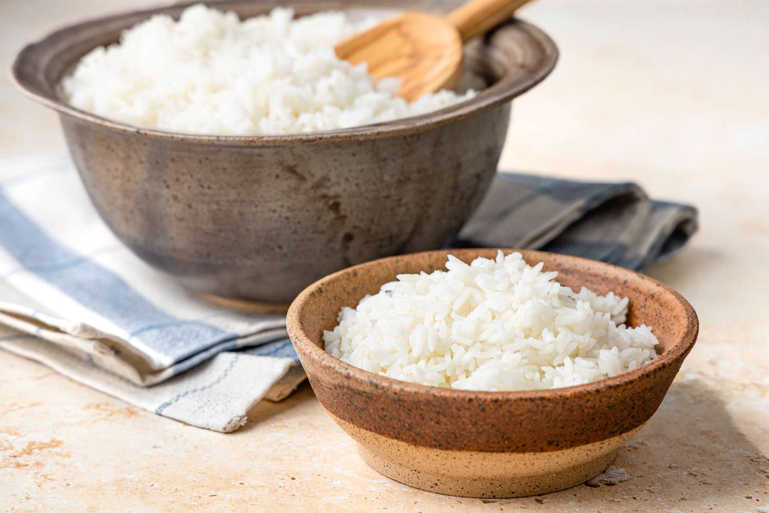 Small Bowl of Microwave Rice, and in the Background, a Larger Bowl with a Wooden Spoon in It 