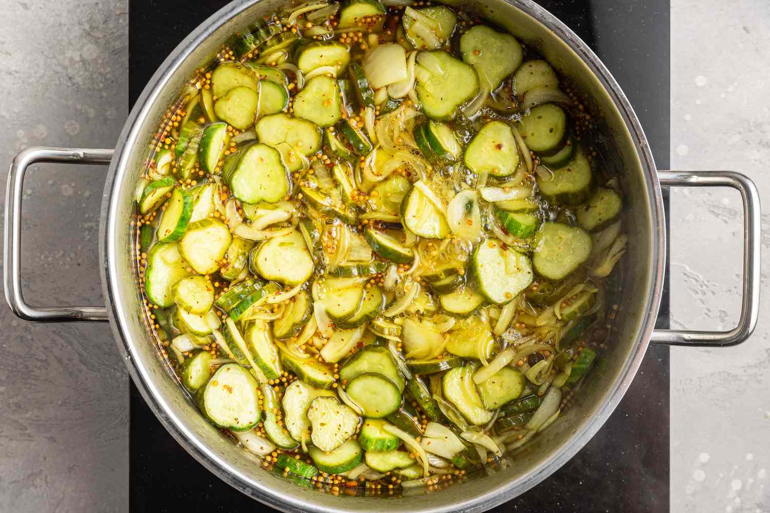 Cucumbers, onions, and other pickling Ingredients in a boiling Pot of water