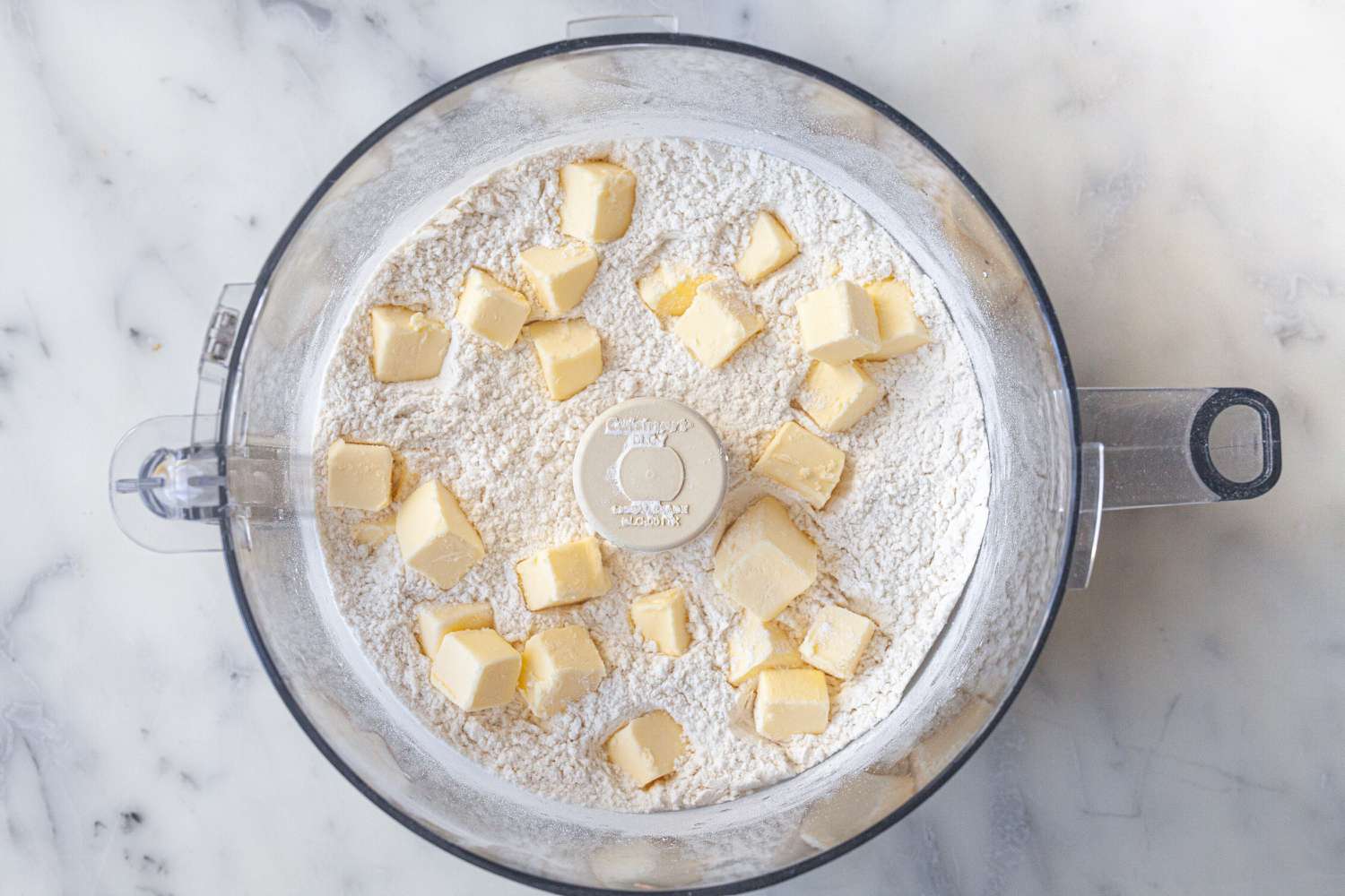 Food processor with cubed butter and flour to make a pie crust recipe butter.