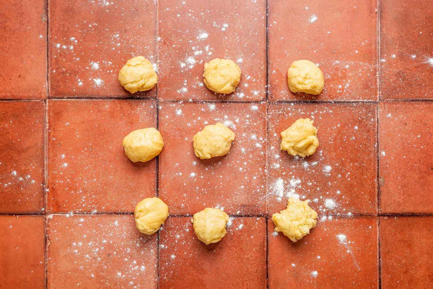 9 small dough balls on a lightly dusted counter