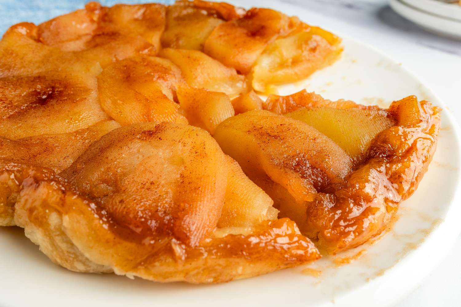 A tarte Tatin with caramelized fruit on a plate partially sliced