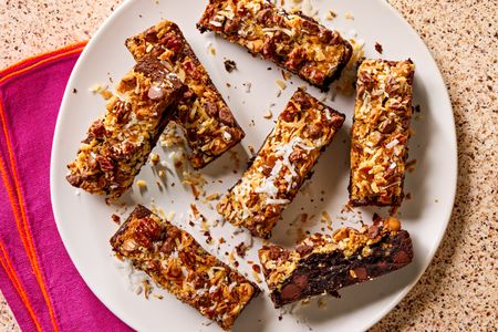 Overhead view of hello dolly brownie bars on a white plate on a brown countertop