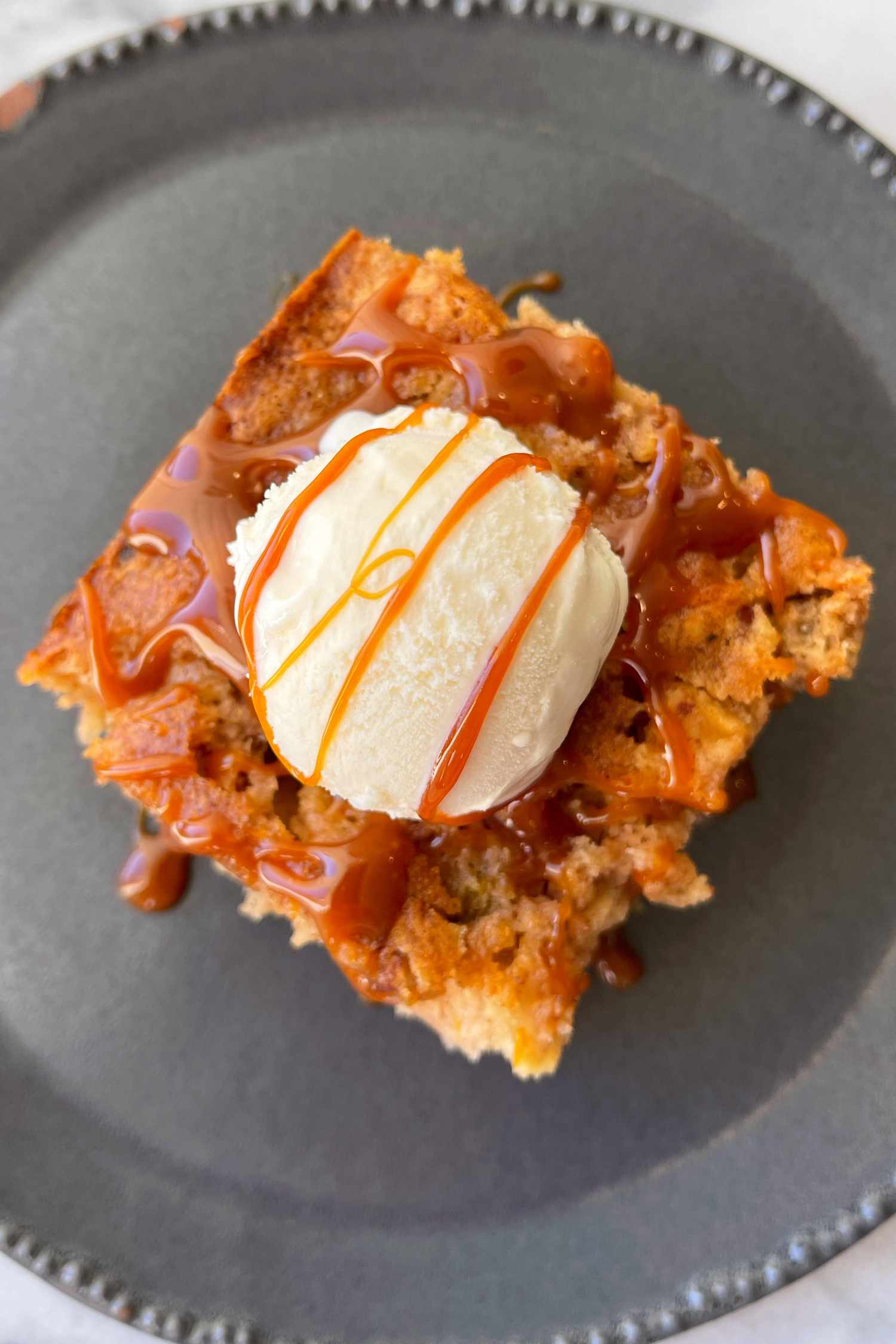 Slice of Ina Garten's apple cake topped with vanilla ice cream and caramel sauce 
