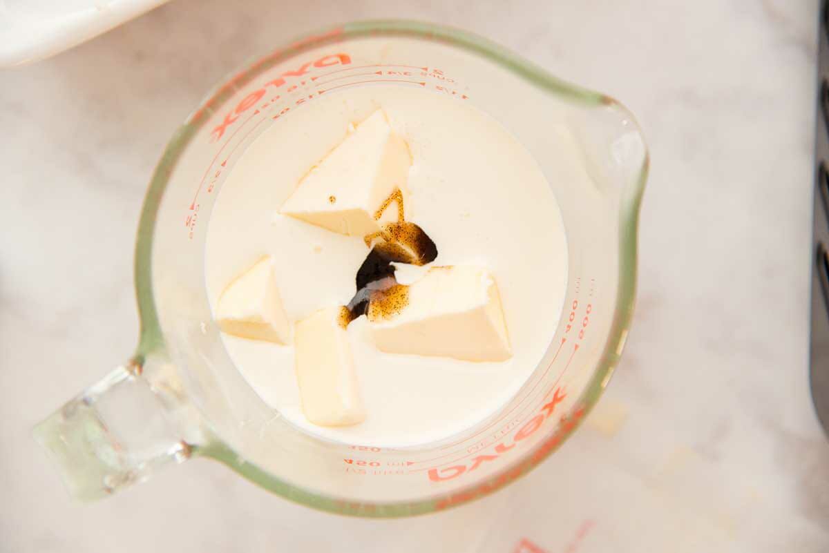 A liquid measuring cup with cream, vanilla and butter to make a Soft Caramel Candy recipe.