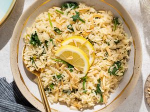 Overhead shot of a plate with lemony spinach rice, topped with two lemon slices