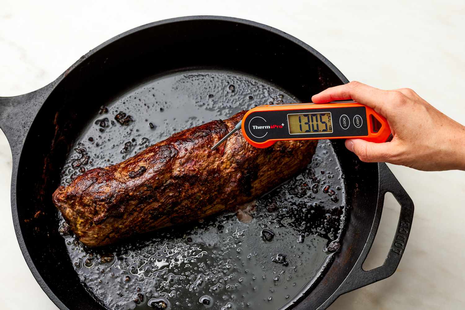 Digital Thermometer Used to Check Internal Temperature of Roasted Fillet of Beef in a Cast Iron Skillet