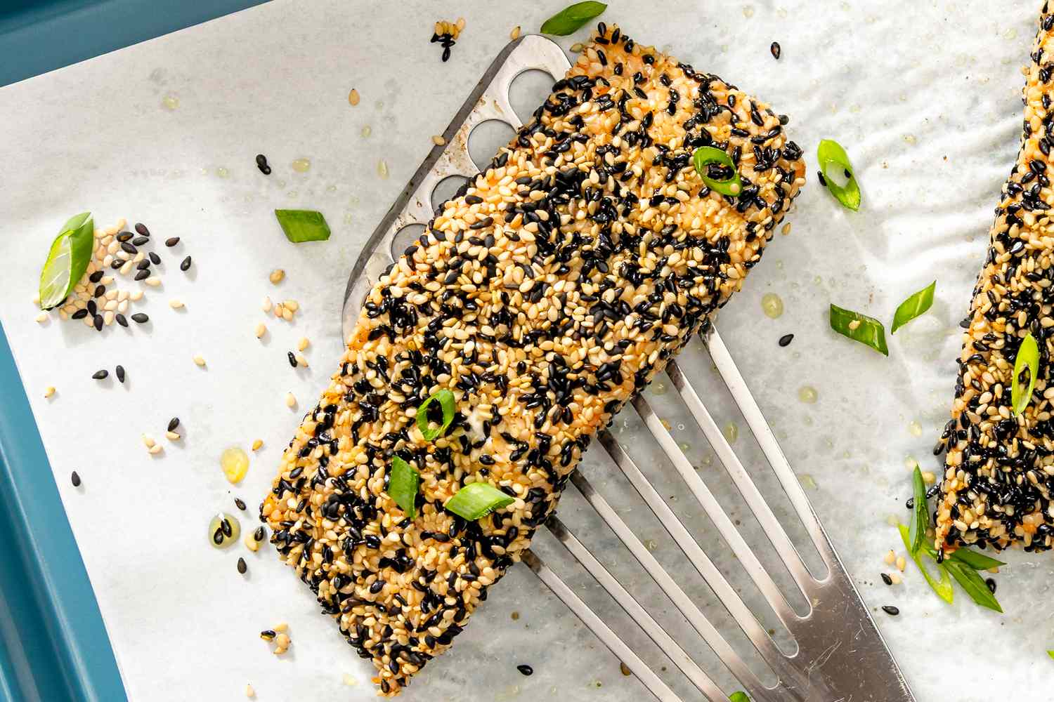A sesame-crusted salmon filet being served with scallions