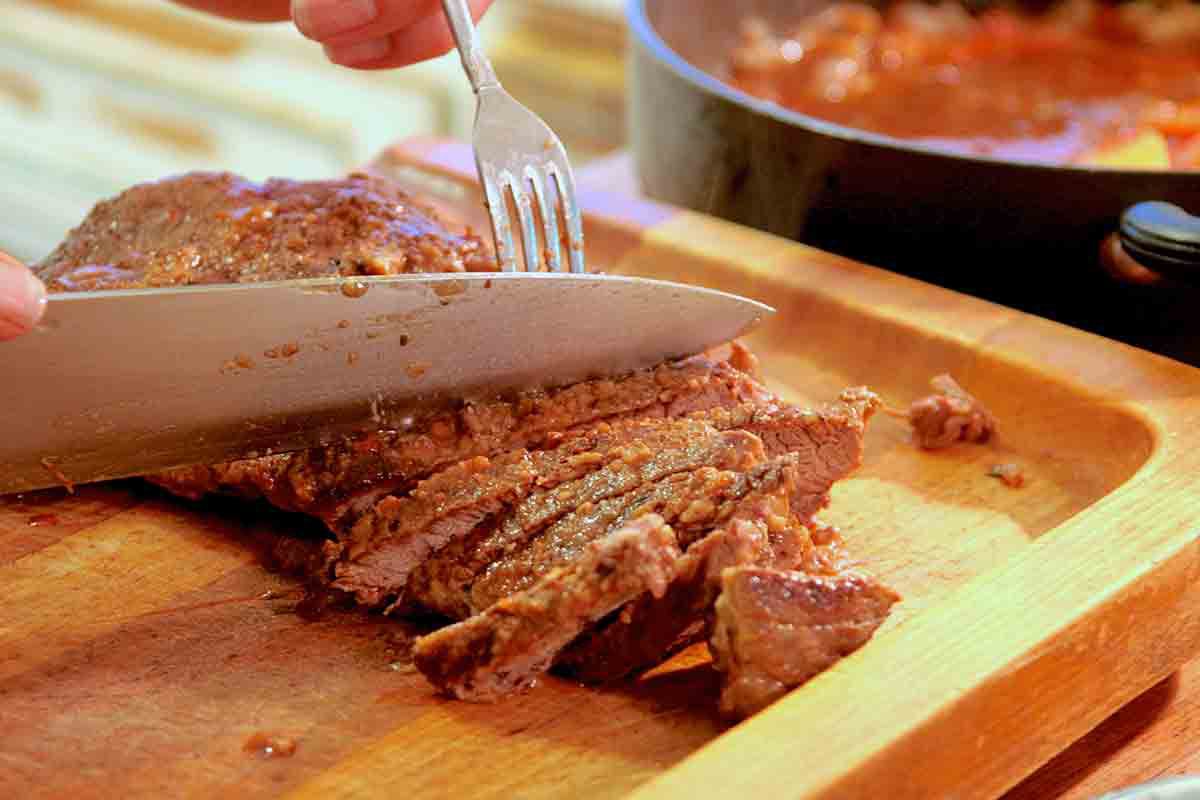Steak being sliced with a knife on a cutting board