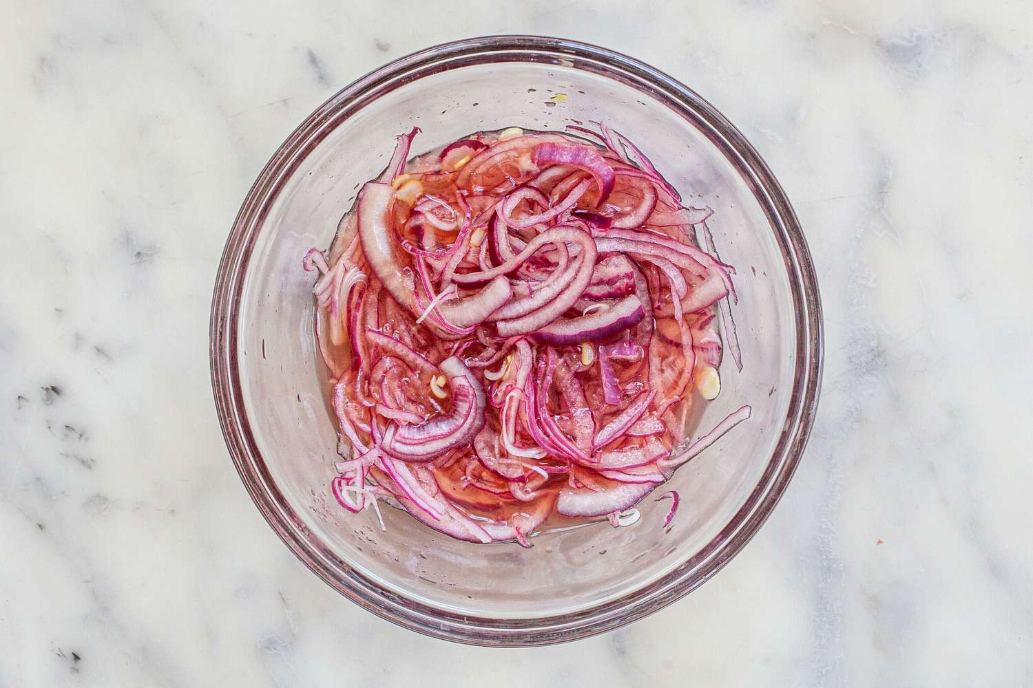 Red onions pickling in a glass bowl to make Crispy Oven Baked Fish Sandwiches.